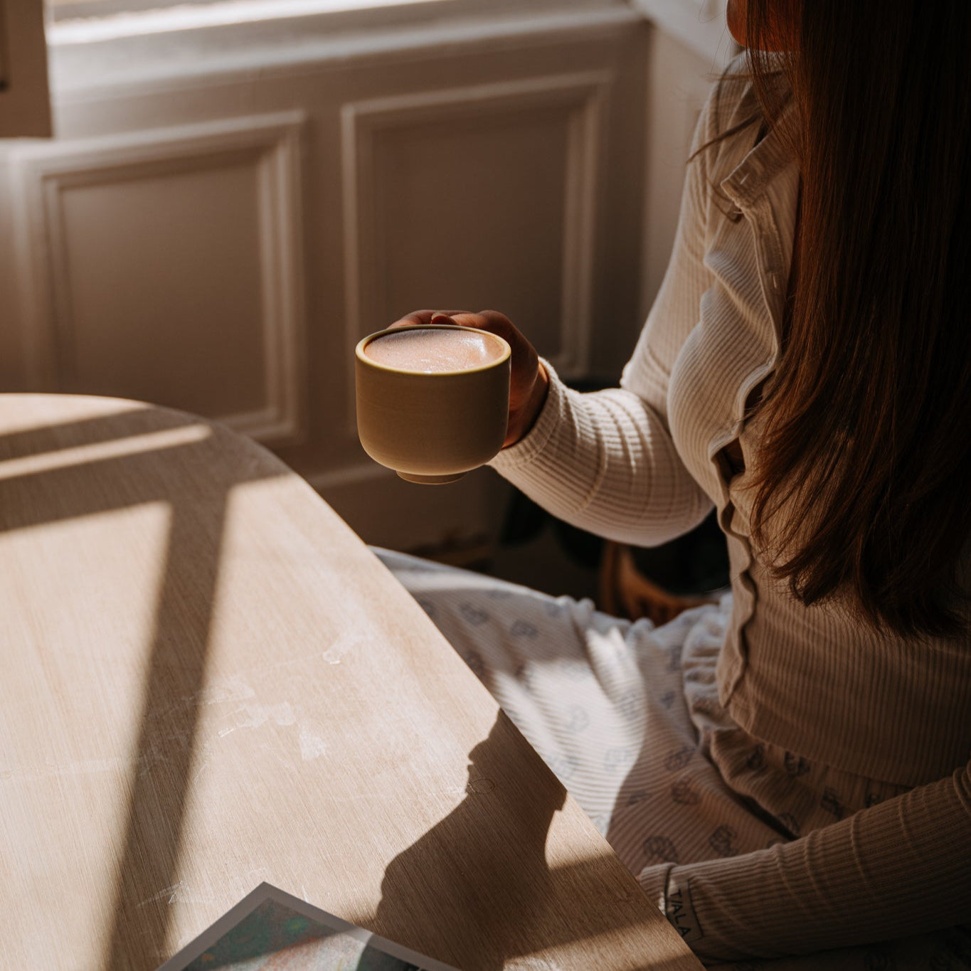 Nibbed hot cacao in mug, girl looking out window